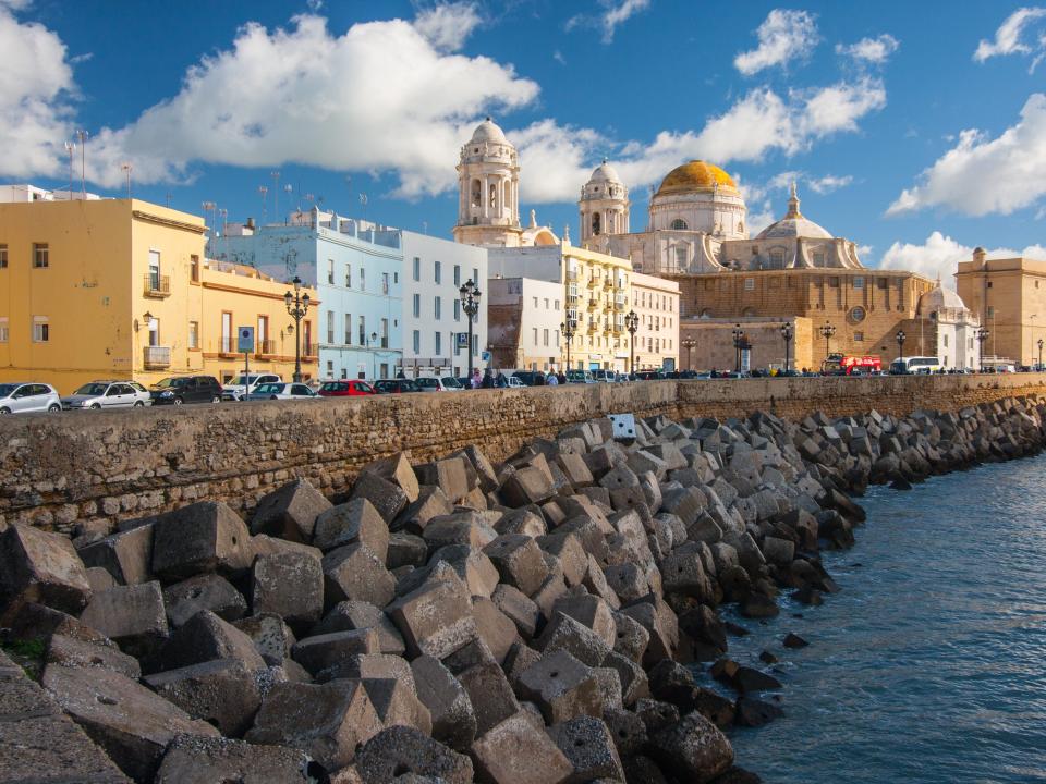 A view of Cadiz, Spain with water, rocks, and Spanish architecture