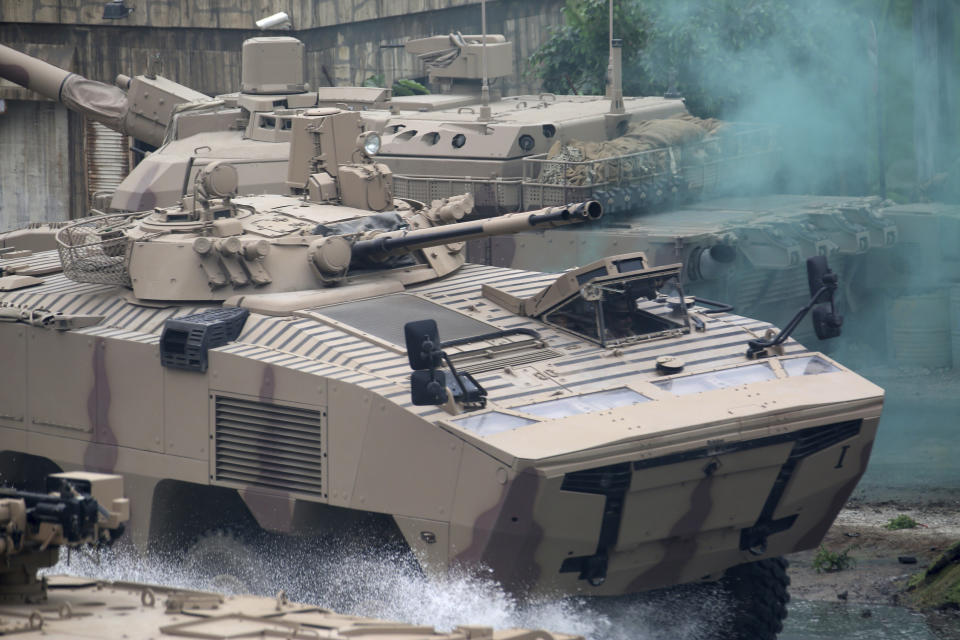 Soldiers in an armored personnel carrier roar through a military demonstration at the International Defense Exhibition and Conference in Abu Dhabi, United Arab Emirates, Sunday, Feb. 17, 2019. The biennial arms show in Abu Dhabi comes as the United Arab Emirates faces increasing criticism for its role in the yearlong war in Yemen. (AP Photo/Jon Gambrell)