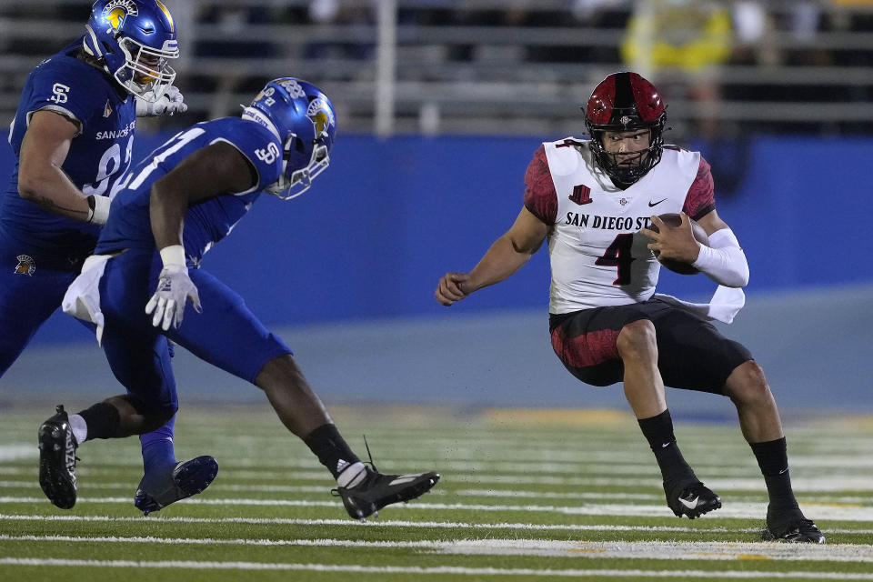 San Diego State quarterback Jordon Brookshire (4) scrambles away from San Jose State safety Jay Lenard (27) and defensive lineman Cade Hall, left, during the first half of an NCAA college football game Friday, Oct. 15, 2021, in San Jose, Calif. (AP Photo/Tony Avelar)