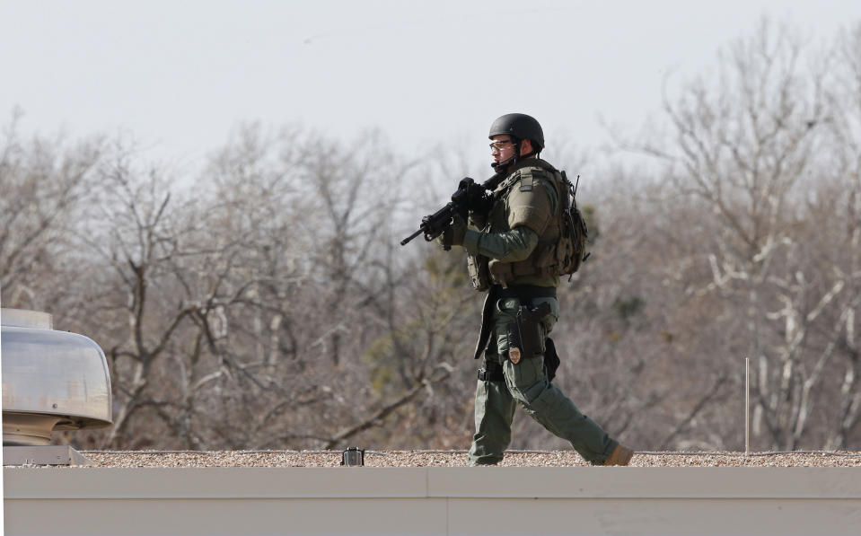 A police officer walks on the roof of Gould Hall at the University of Oklahoma in Norman, Okla., as the area was closed down following reports of gunfire Wednesday, Jan. 22, 2014. The University of Oklahoma says authorities found no evidence of shots being fired on campus and no injuries have been reported. (AP Photo/Sue Ogrocki)