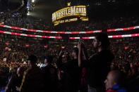 FILE - Wrestling fans, under a Wrestlemania sign, watch a WWE Monday Night RAW event, March 6, 2023, in Boston. This year's WrestleMania may be just days away, but the marketing run up to WWE's biggest premium live event went into overdrive months ago. (AP Photo/Charles Krupa, File)