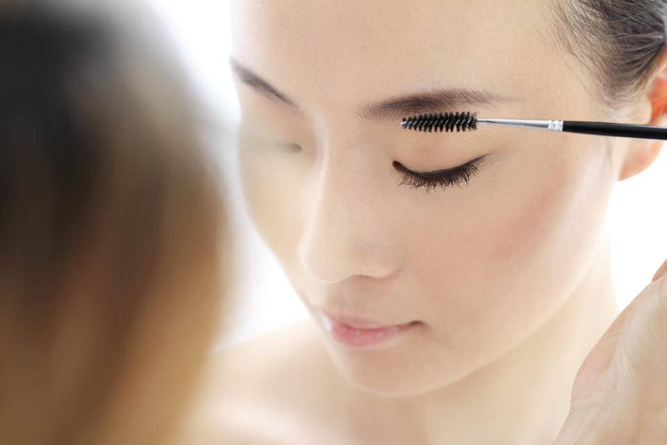 Young woman applying makeup with a brush. (PHOTO: Getty Images)