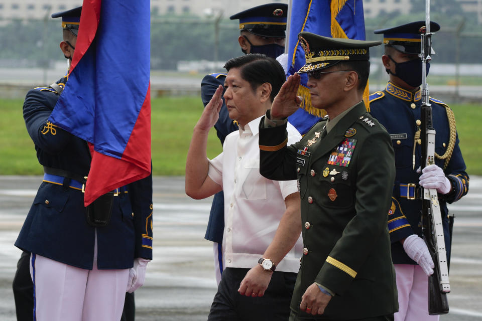 Philippine President Ferdinand Marcos Jr., left, salutes during departure honors as he boards a plane for China on Tuesday, Jan. 3, 2023, at the Villamor Air Base in Manila, Philippines. (AP Photo/Aaron Favila)