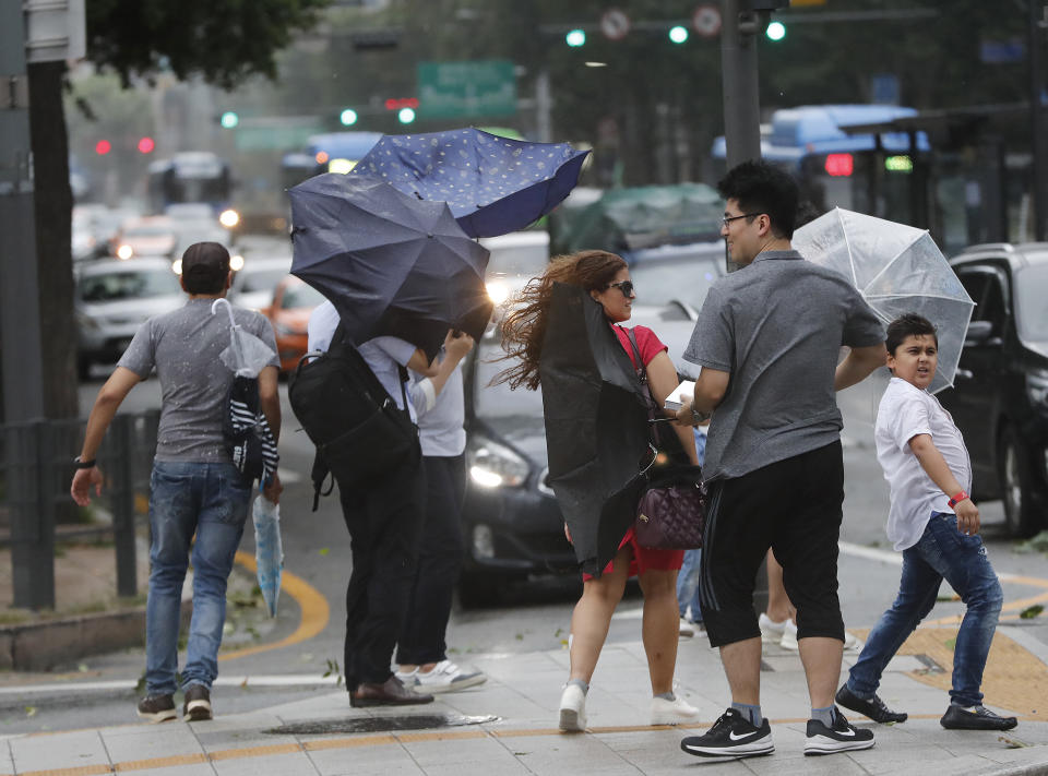 People hold umbrellas against the strong wind and rain caused by Typhoon Lingling in Seoul, South Korea, Saturday, Sept. 7, 2019. The typhoon passed along South Korea's coast Saturday, toppling trees, grounding planes and causing at least two deaths before the storm system made landfall in North Korea. (AP Photo/Ahn Young-joon)