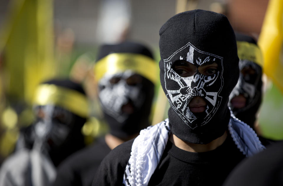 Masked Palestinians march during a celebration marking the 55th anniversary of the Fatah movement, in the West Bank city of Ramallah, Tuesday, Dec. 31, 2019. (AP Photo/Majdi Mohammed)