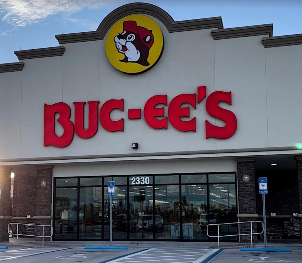 The storefront of a Buc-ee's which has disabled-parking spaces and a large logo of the store's mascot, a squirrel wearing a red cap.