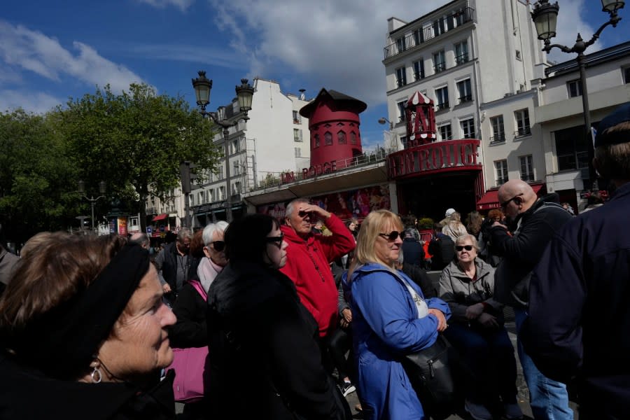 People walk past the Moulin Rouge (Red Mill) Thursday, April 25, 2024 in Paris. The windmill from the Moulin Rouge, the 19th century Parisian cabaret, has fallen off the roof overnight along with some of the letters in its name. (AP Photo/Thibault Camus)