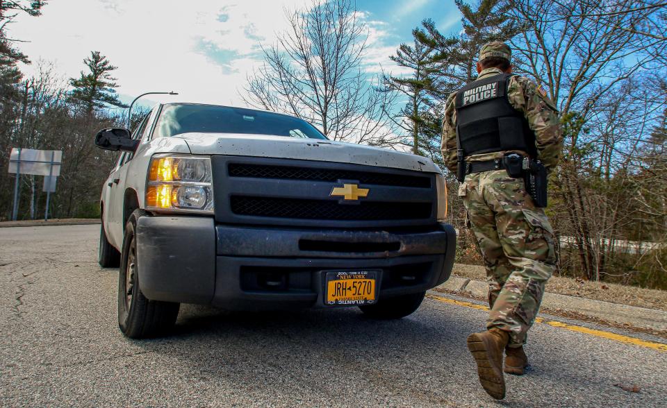 In late March 2020, a member of the Rhode Island National Guard stops a car with New York plates at a Westerly rest stop to help enforce the state's COVID-19 quarantine restrictions.