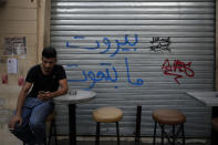 A man checks his mobile phone as he sits outside a bar in the Mar Mikhael neighborhood in Beirut, Lebanon, Saturday, July 17, 2021. A year after a deadly blast at the Beirut port killed more than 200 people, families of the victims are consumed with winning justice for their loved ones and punishing Lebanon's political elite, blamed for causing the disaster through their corruption and neglect. (AP Photo/Hassan Ammar)