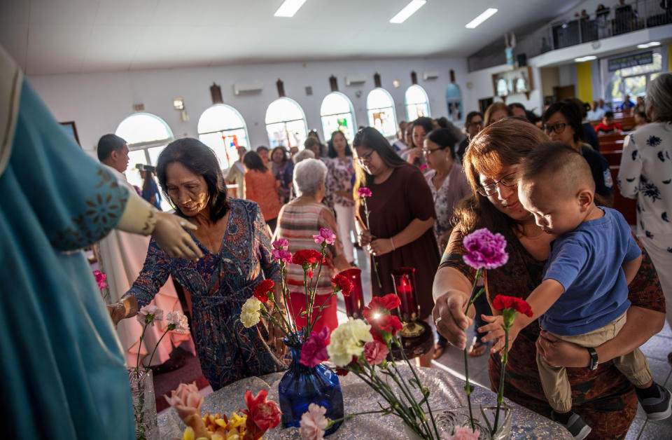 Jeanie Bamba holds her grandson, Jayce, as they lay flowers at a statue of the Virgin Mary during a Mass on Mother's Day at Immaculate Heart of Mary Catholic Church in Toto, Guam, Sunday, May 12, 2019. Nearly four centuries after the arrival of the first Jesuit missionaries, Catholicism is deeply engrained in Chamorro culture. More than 85 percent of Guam's 165,000 residents identify as Catholic. By comparison, the most Catholic city on the mainland, Boston, is 36 percent. (AP Photo/David Goldman)