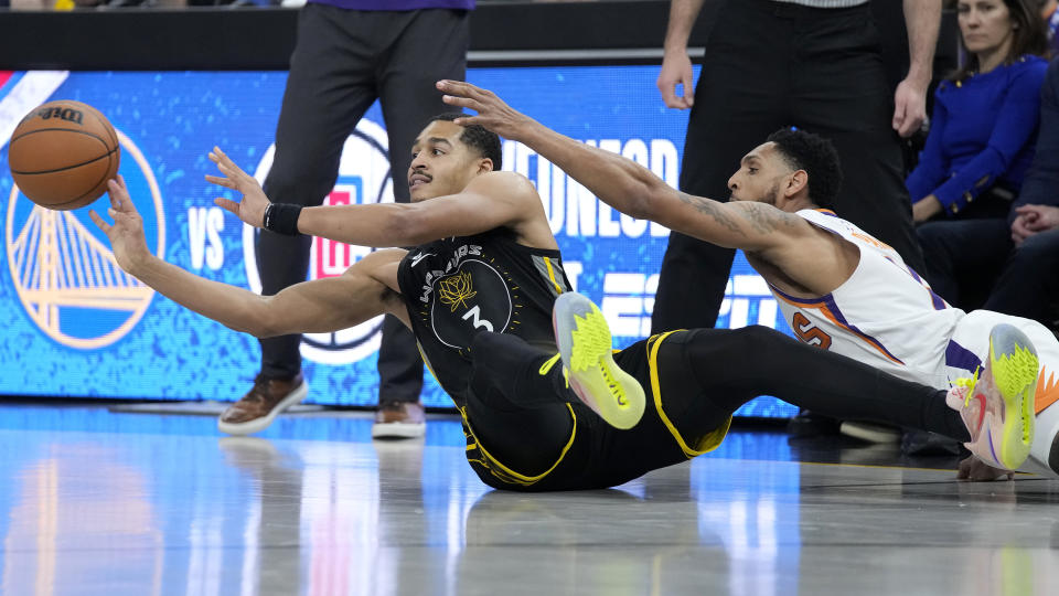 Golden State Warriors guard Jordan Poole (3) passes the ball next to Phoenix Suns guard Cameron Payne during the first half of an NBA basketball game in San Francisco, Monday, March 13, 2023. (AP Photo/Jeff Chiu)