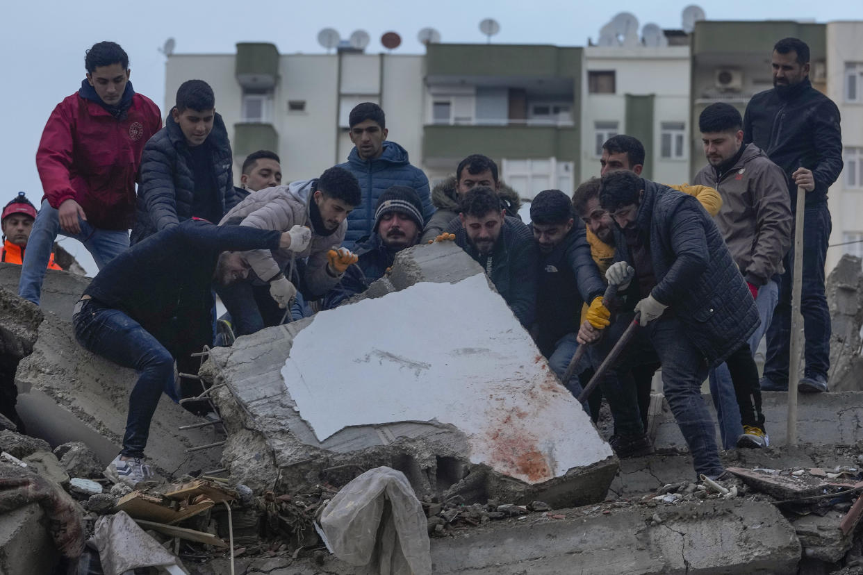 Men search for people among the debris in a destroyed building in Adana, Turkey, Monday, Feb. 6, 2023. (AP Photo/Khalil Hamra)