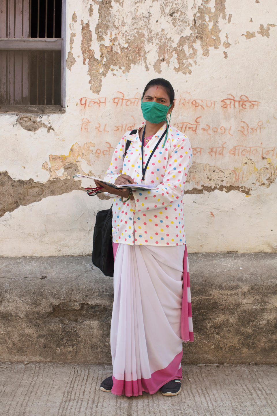 Portrait of Archana Ghugare, a community health worker, in Pavnar, Maharashtra, India, on Dec. 1, 2020. In the background is a message encouraging people to bring their children for the Polio vaccine drive.<span class="copyright">Prarthna Singh for TIME</span>