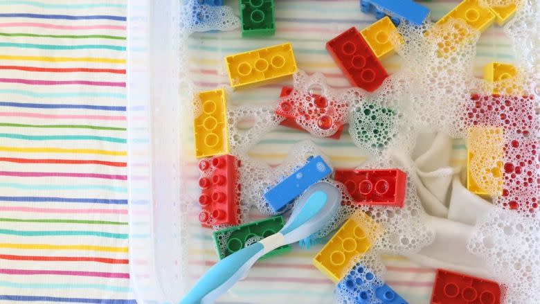 a bin is filled with water, soap, duplo blocks and a scoop