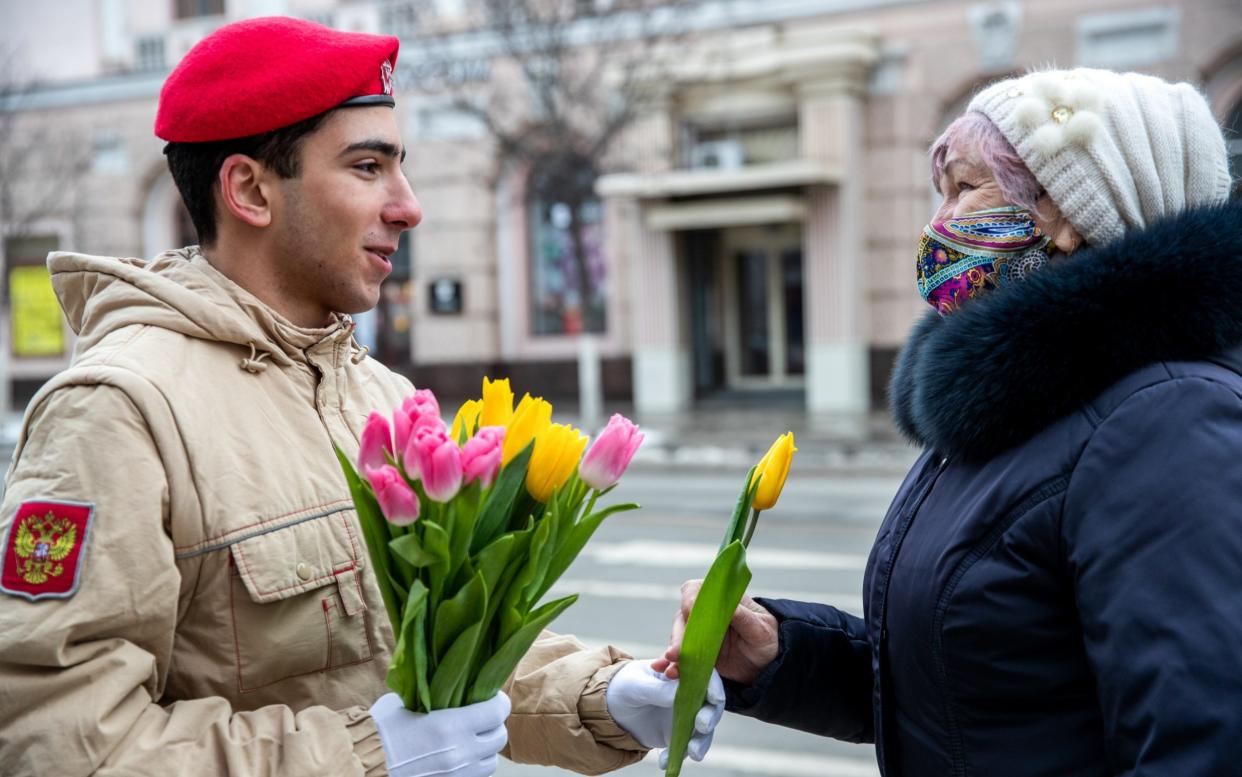 A member of Russia's Young Army Cadets National Movement gives flowers to a woman for International Women's Day  - Erik Romanenko\\TASS via Getty Images