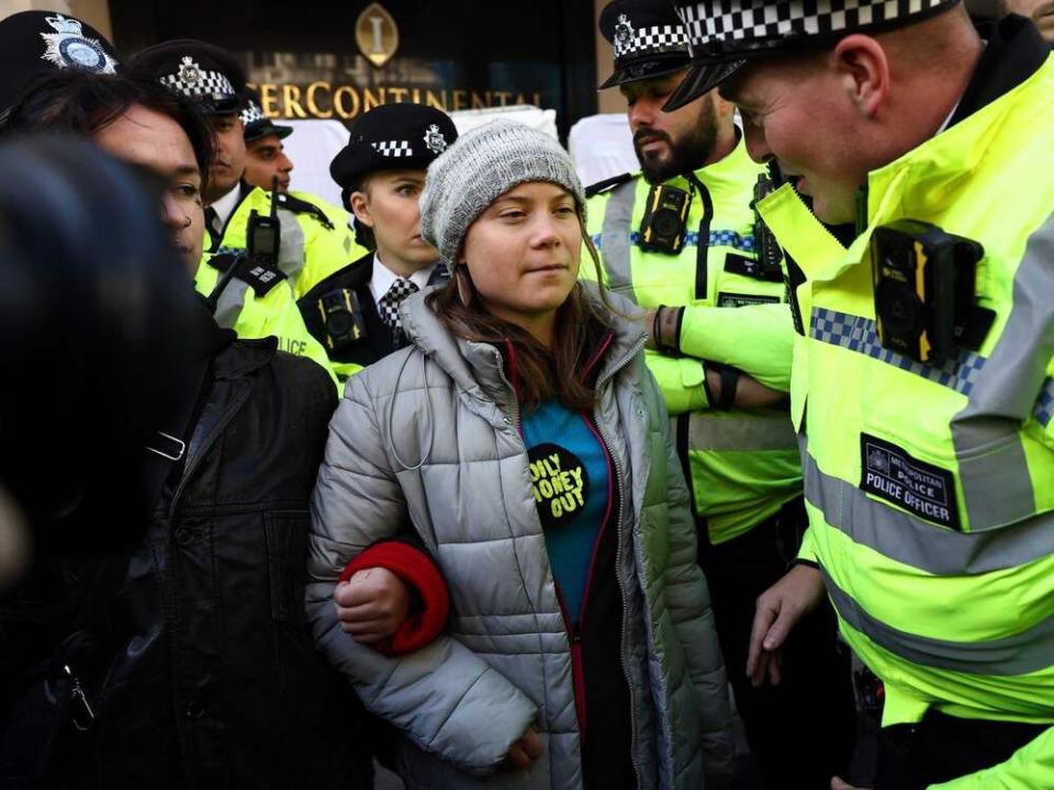  A police officer speaks to Swedish climate activist Greta Thunberg moments before being arrested outside the InterContinental London Park Lane.