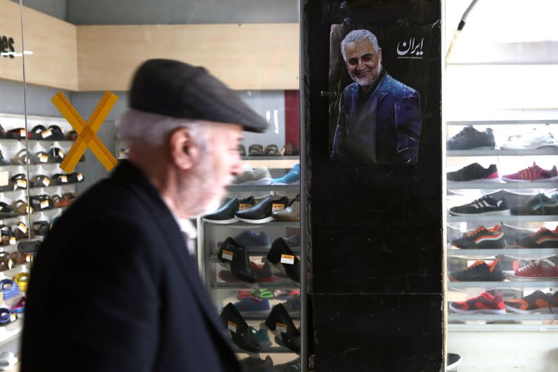 FILE PHOTO: A man walks past a picture of Iranian Major-General Qassem Soleimani, head of the elite Quds Force, who was killed in an air strike at Baghdad airport, in Tehran