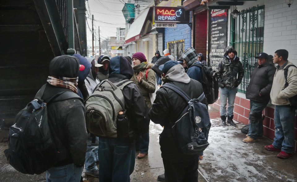 Adriana Escandon, center, a coordinator with the New Immigrant Community Empowerment (NICE), speaks to a group of day laborers before a distribution of hot rice pudding and safety items on Tuesday, Dec. 17, 2013 in Queens, N.Y. NICE provide services for day laborers and the undocumented, including OSHA training, english language classes and legal advice. "Labor laws in this country make it possible that alll these workers have the same rights, regardless of immigration status," said Escandon. (AP Photo/Bebeto Matthews)