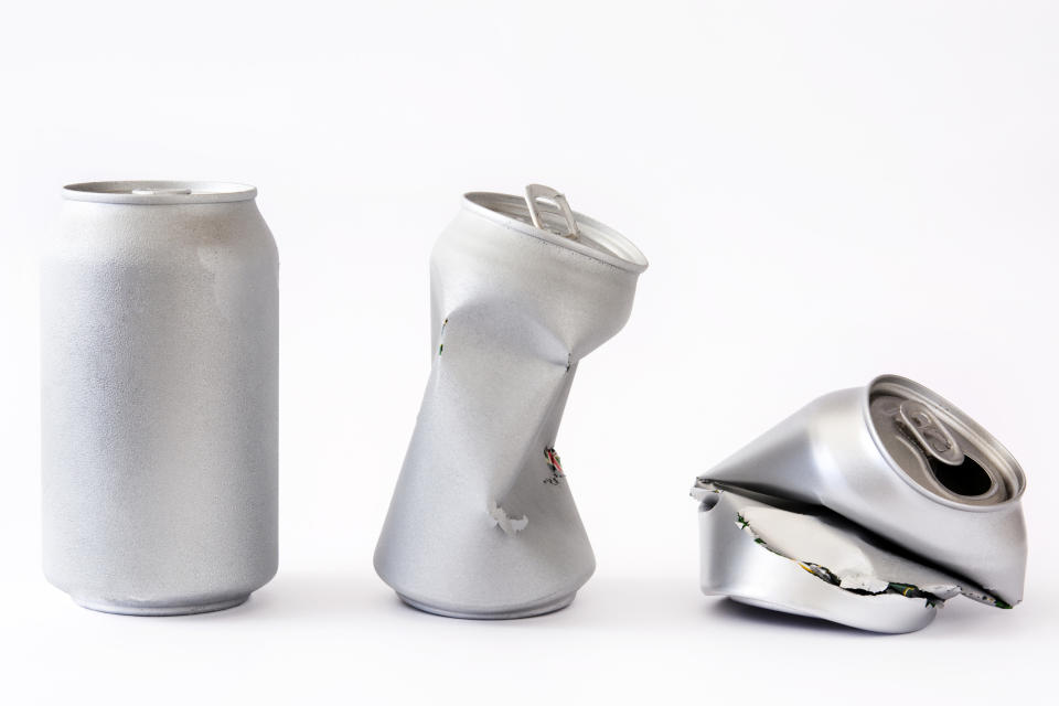 An intact beverage can, a partially crushed beverage can, and a fully crushed beverage can