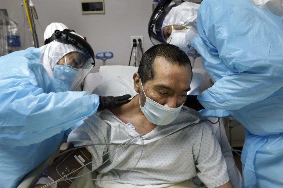 COVID unit nurse Anita Pandey, left, and medical student volunteer Alan Araiza check bruises on Melequiades Cervantes' back.