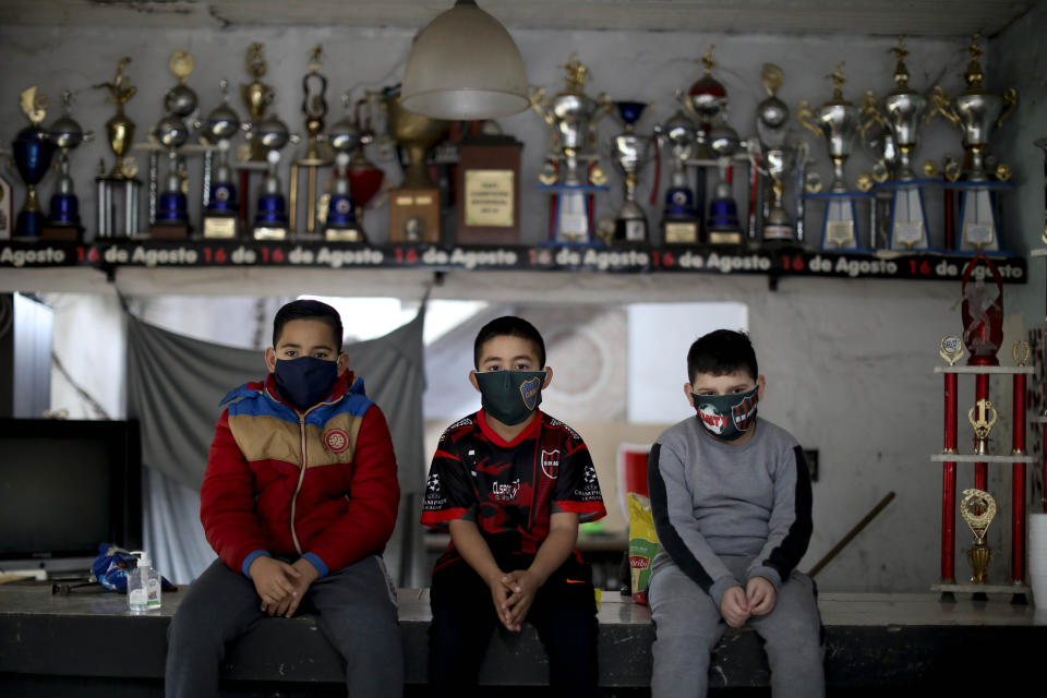 Desde la izquierda, Daniel Rocaro, Uriel López y Bauti Fernández, niños promesas del fútbol, posan para una foto frente a sus trofeos durante una entrevista en su club "16 de Agosto", donde solían jugar antes del confinamiento para frenar el COVID-19 en el barrio de Villa Caraza en Buenos Aires, Argentina, el martes 9 de junio de 2020. (AP Foto/Natacha Pisarenko)