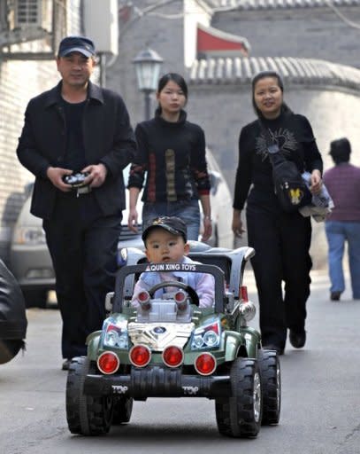 A baby boy sitting in a luxury toy car, riding next to his family along a street in Beijing on October 21. China's one-child policy has prevented almost half a billion births but has turned into a demographic time bomb as the population ages, storing up huge economic and social problems for the country