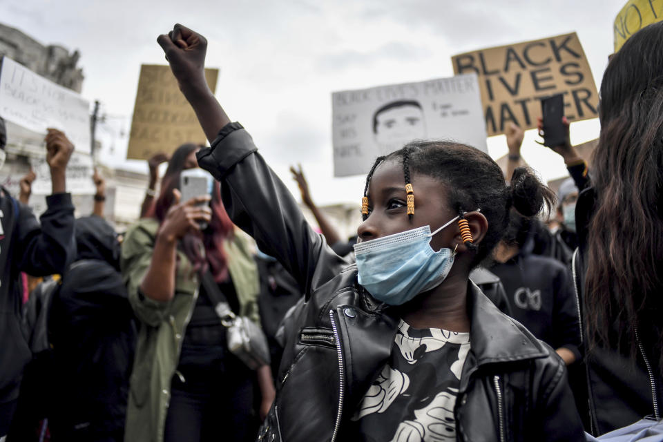 A girl clinches her fist as people gather to honor George Floyd, who died May 25 after being restrained by police in Minneapolis, USA, in Milan, Italy, Sunday, June 7, 2020. In Italy’s financial capital, Milan, a few thousand protesters gathered in a square outside the central train station Sunday afternoon to demonstrate against racism. (Claudio Furlan/LaPresse via AP)