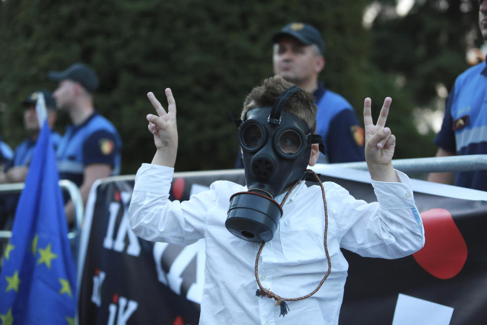 A child wears a gas mask as he flashes the victory sign during an anti-government protest in Tirana, Albania, Saturday, June 8, 2019. Thousands of Albanian opposition supporters are gathering in an anti-government protest while the United States and the European Union caution their leaders to disavow violence and sit in a dialogue to overcome the political crisis. (AP Photo/Hektor Pustina)