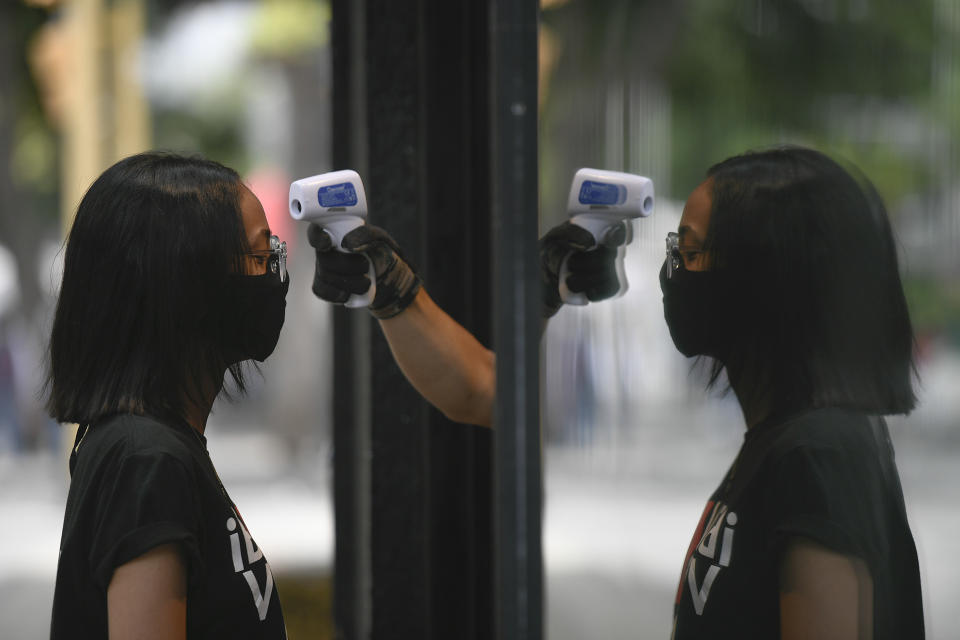 A store employee measures the temperature of a woman before allowing her to enter the shop amid the new coronavirus pandemic in Caracas, Venezuela, Saturday, July 25, 2020. The Venezuelan opposition hoped that 2020 could bring new momentum after several failed pushes to overthrow President Nicolas Maduro, but then came the coronavirus, which analysts say has helped suck away the opposition’s scanty momentum and bolster Maduro’s already strong hand. AP Photo/Matias Delacroix)