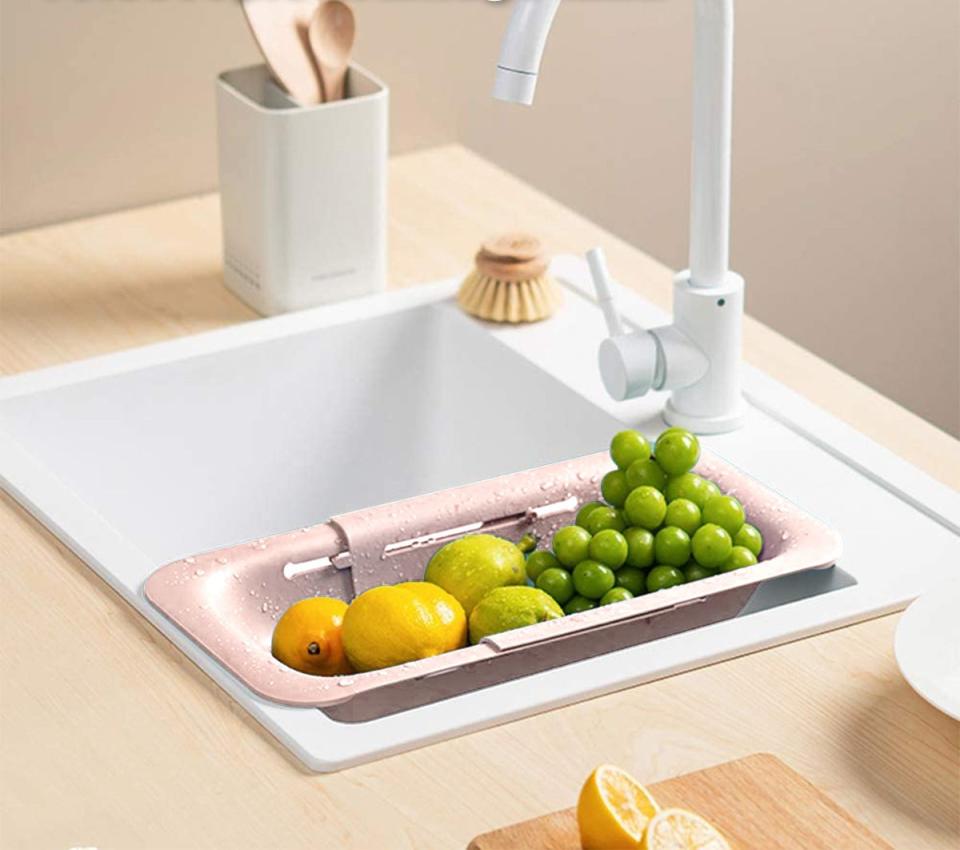 the colander in pink over a sink with fruit in it
