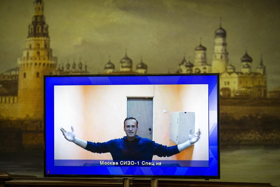 FILE - In this Jan. 28, 2021, file photo, Russian opposition leader Alexei Navalny appears on a TV screen during a court hearing appealing his jailing, with an image of the Kremlin in the background in Moscow, Russia. Navalny was jailed when he arrived in Moscow on Jan. 17, after authorities accused him of violating the terms of his parole on a 2014 fraud conviction. (AP Photo/Alexander Zemlianichenko, File)