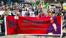 In this photo provided by Kurdish-run Hawar News Agency, Kurdish women hold a banner and portraits of Iranian Mahsa Amini during a protest condemning her death in Iran, in the city of Qamishli, northern Syria, Monday, Sept. 26, 2022. Protests have erupted across Iran in recent days after Amini, a 22-year-old woman, died while being held by the Iranian morality police for violating the country's strictly enforced Islamic dress code. The banner in Arabic reads, "We vow to take revenge against the vicious femicide." (Hawar News Agency via AP via AP)