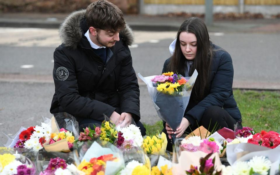 A couple place a bunch of flowers with the floral tributes outside the home of Captain Sir Tom Moore  - Kirsty O'Connor/PA