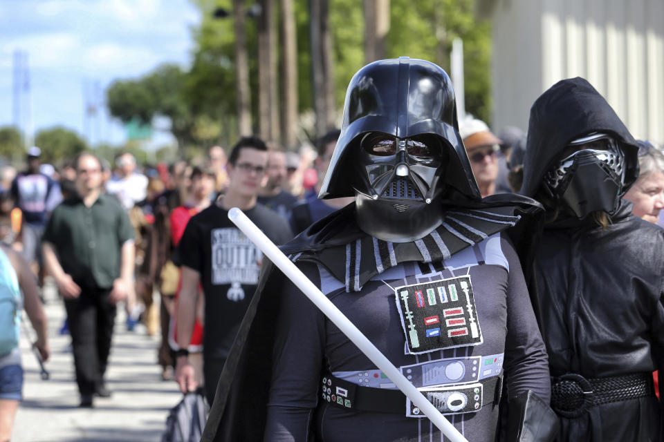 Costumed fans of the "Star Wars" franchise wait in line outside the Orange County Center, in Orlando, Fla., to attend the 2017 Star Wars Celebration, Thursday, April 13, 2017, marking the 40th anniversary of the original 1977 Star Wars film. Thousands of fans waited for hours in the line, estimated to be more than a mile long. (Joe Burbank/Orlando Sentinel via AP)