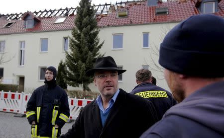 Markus Nierth (C), former mayor of Troeglitz, talks to fire-fighters in front of a building that was meant to be an asylum shelter, which was damaged in a fire, in Troeglitz April 4, 2015. REUTERS/Fabrizio Bensch