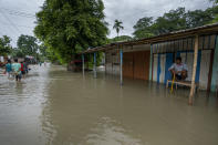 A man sits on a table as villagers wade through floodwaters in Alekjari village, west of Gauhati, India, Saturday, June 18, 2022. More than a dozen people have died as massive floods ravaged northeastern India and Bangladesh, leaving millions of homes underwater and severing transport links, authorities said Saturday. (AP Photo/Anupam Nath)
