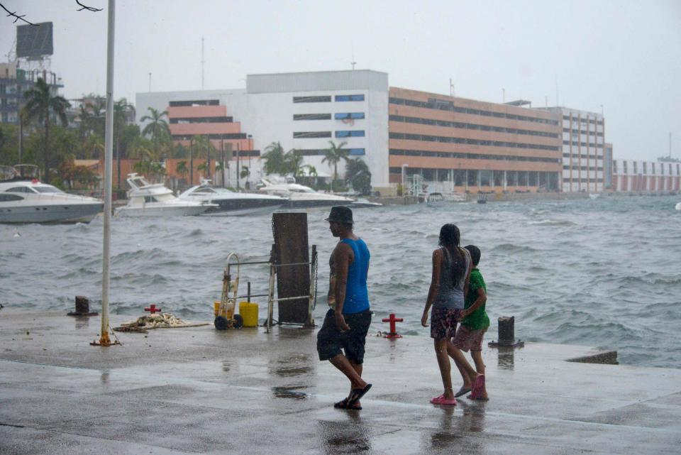 People walk along the coast in Acapulco, Guerrero State, Mexico, on August 16, 2023, following the passage of Tropical Storm Hilary.