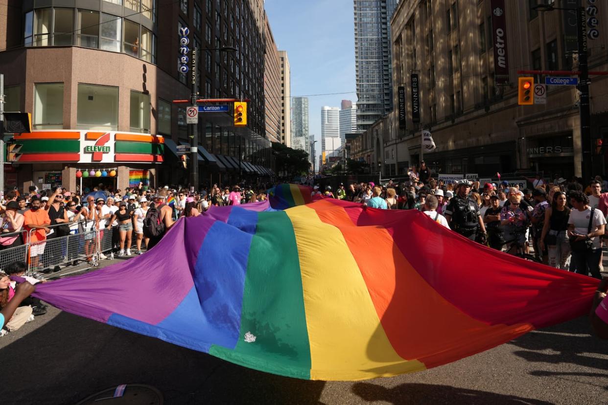 Participants carry a pride flag as they walk in the Toronto Pride Parade, on Sunday June 25, 2023. Pride Toronto, the organization that runs the parade each year, is repaying funding to the federal government after an accounting firm found the organization could not prove that it completed several projects. (Chris Young/Canadian Press - image credit)