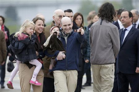 Nicolas Henin (C), former French hostage and journalist, points as he is greeted by his family moments after a transfer by helicopter from Evreux to the military airbase in Villacoulbay, near Paris, April 20, 2014. REUTERS/Philippe Wojazer