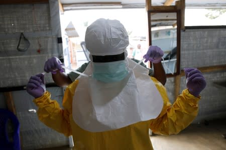 FILE PHOTO: A health worker puts on Ebola protection gear before entering the Biosecure Emergency Care Units at the Alima Ebola treatment centre in Beni