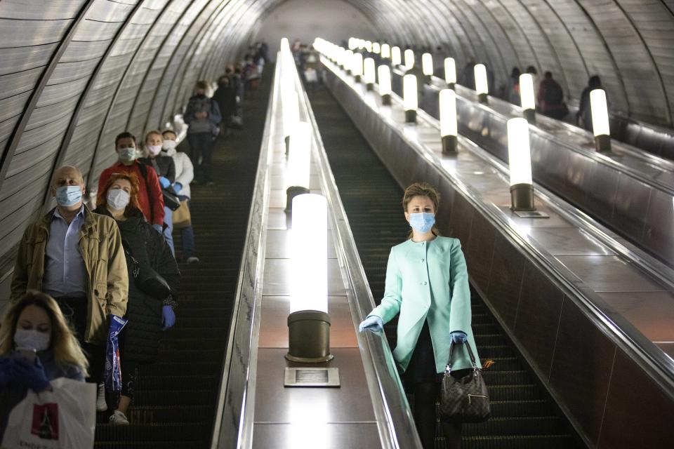 People wearing face masks and gloves to protect against coronavirus, observe social distancing guidelines as they go down the subway on the escalator in Moscow, Russia, Tuesday, May 12, 2020. From Tuesday onward, wearing face masks and latex gloves is mandatory for people using Moscow's public transport. President Vladimir Putin on Monday declared an end to a partial economic shutdown across Russia due to the coronavirus pandemic, but he said that many restrictions will remain in place. (AP Photo/Alexander Zemlianichenko)