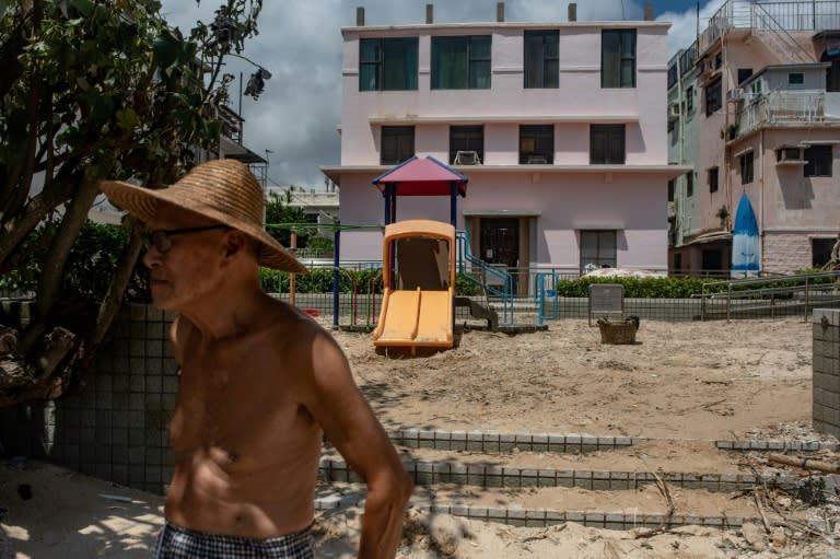 A man stands in front of a playground filled with sand in Shek O