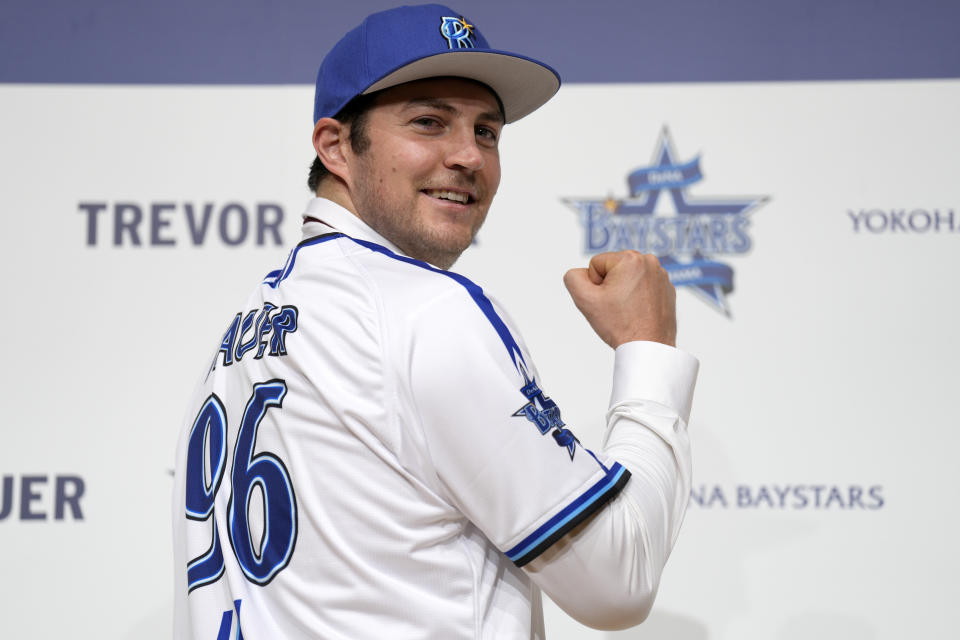 Trevor Bauer with his new uniform and cap of Yokohama DeNA BayStars poses for photographers during a photo session of the news conference Friday, March 24, 2023, in Yokohama, near Tokyo. (AP Photo/Eugene Hoshiko)