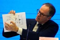 In this Feb. 9, 2021, file photo, Peter Ben Embarek of the World Health Organization team holds up a chart showing pathways of transmission of the virus during a joint news conference at the end of the WHO mission in Wuhan in central China's Hubei province. A joint WHO-China study on the origins of COVID-19 says that transmission of the virus from bats to humans through another animal is the most likely scenario and that a lab leak is "extremely unlikely," according to a draft copy obtained by The Associated Press.