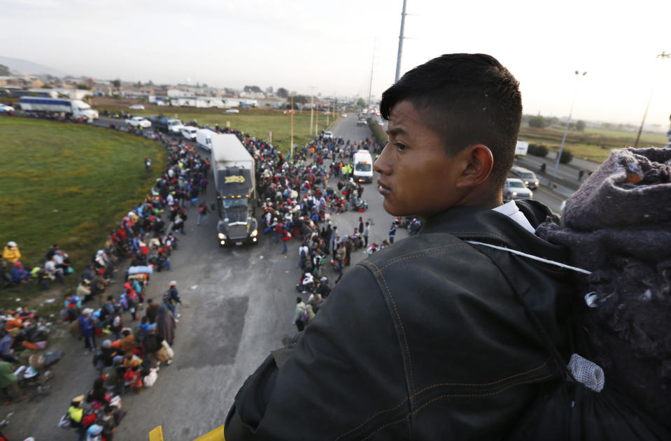 Un migrante centroamericano, parte de la caravana que espera llegar a la frontera con Estados Unidos, mira desde un paso elevado mientras otros se montan en camiones en Irapuato, México, el lunes 12 de noviembre de 2018. (AP Foto / Marco Ugarte)