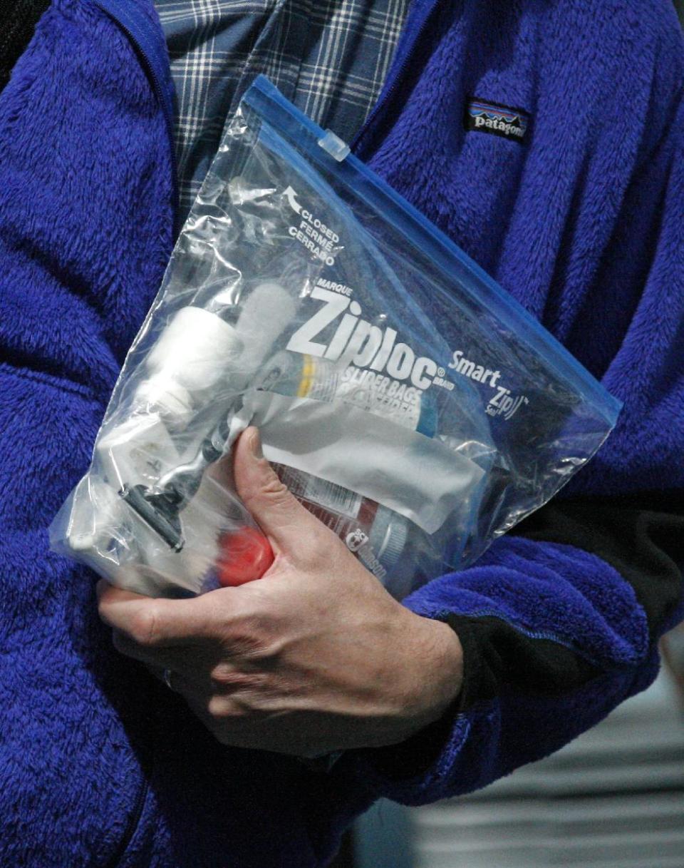 A traveler passing through a security check point holds his Ziploc bag at Portland International Airport Tuesday, May 8, 2012, in Portland, Ore. Airport security procedures, with their intrusive pat downs and body scans, don’t need to be toughened despite the discovery of a new al-Qaida airline bomb plot using more sophisticated technology than an earlier attempt, congressional and security officials said Tuesday. (AP Photo/Rick Bowmer) 