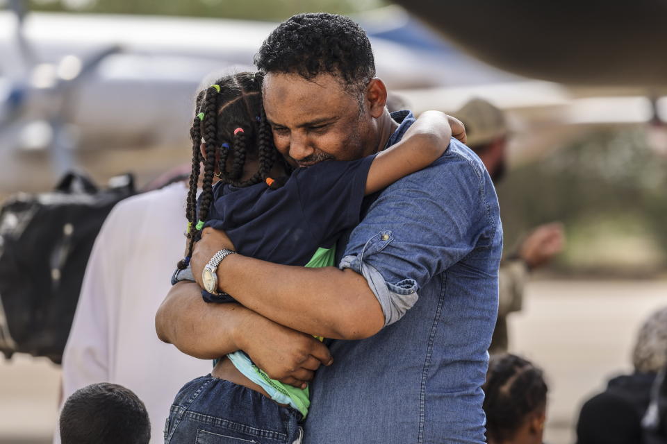 En esta imagen facilitada por el Ministerio de Defensa de Gran Bretaña el jueves 27 de abril de 2023, Violinist Othmano, a la derecha, abraza a su hija antes de que suban a un avión C-130 de la Real Fuerza Aérea, que los llevaría a Chipre desde el aeropuerto militar WadiSeidna, al norte de Jartum, Sudán. (Aaron Hoare/Ministerio de Defensa de Gran Bretaña vía AP)