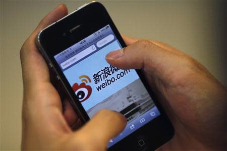 A man uses his phone to visit the Sina Weibo microblogging site in Shanghai, in this file picture taken May 29, 2012. REUTERS/Carlos Barria/Files