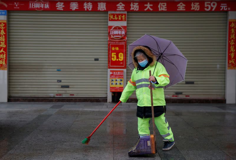 A street cleaner wears a face mask in a deserted shopping street in Jiujiang