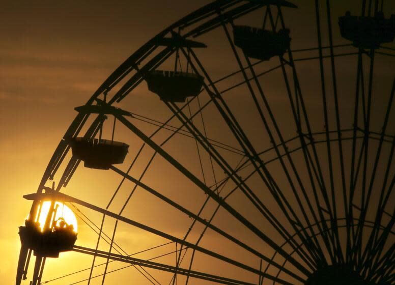 SANTA MONICA, CALIF. - OCT. 17, 2023. Visitors to Pacific Park are silhouetted against the setting sun at Santa Monica Pier on a recent afternoon. Warmer weather is expected throughout Southern California this week. (Luis Sincvo / Los Angeles Times) .